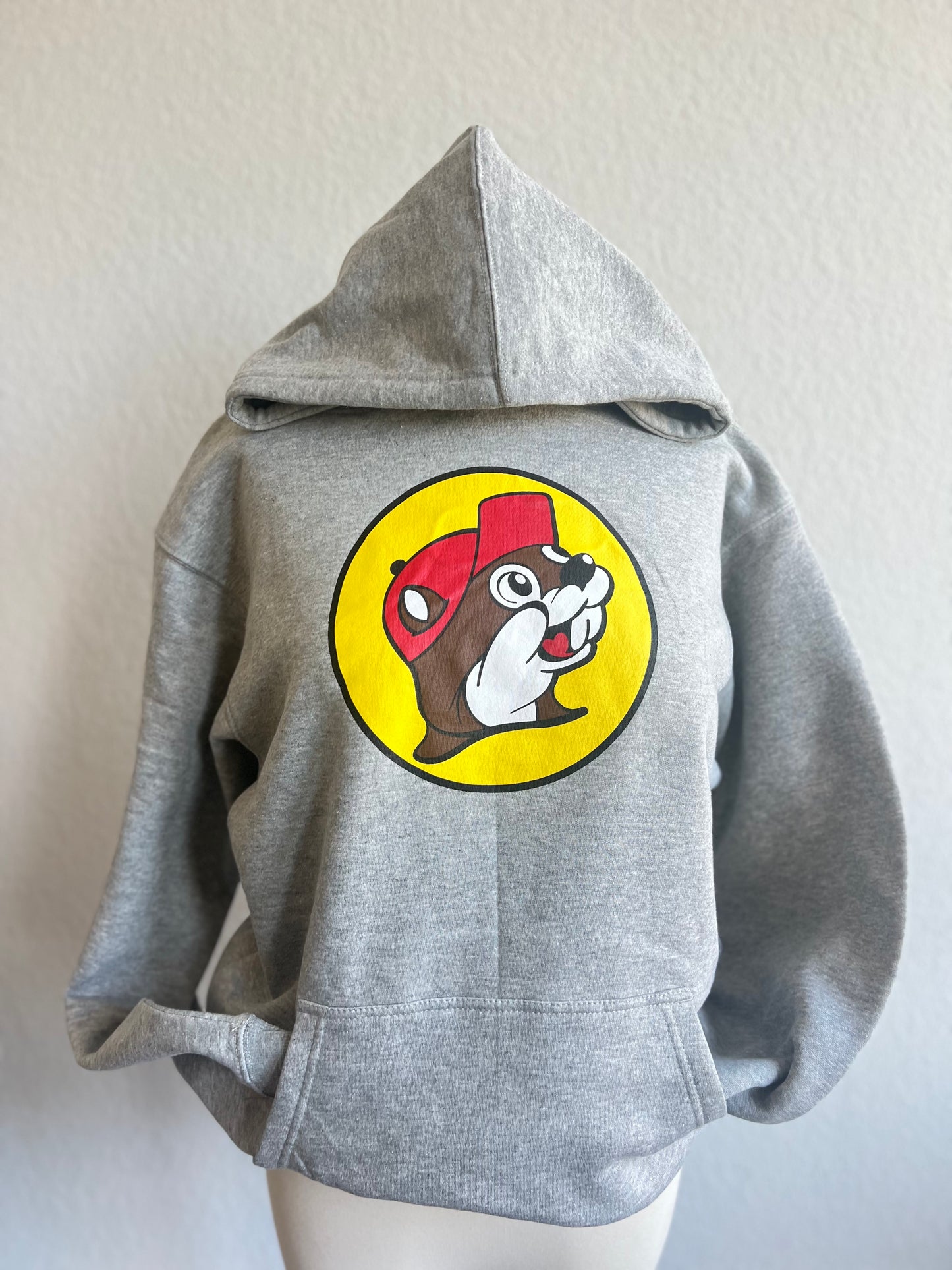 Grey sweatshirt with Buc-ee the Beaver on the front wearing a red hat inside a yellow circle