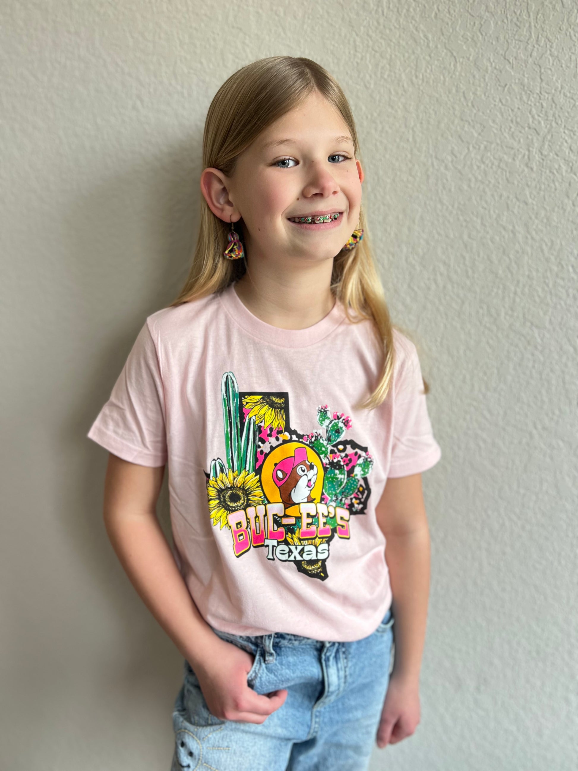 Pink Buc-ee's Texas Desert Shirt. With a Texas state outline filled with sunflowers, cactus, cactus flowers, and leopard spots. There is also a image of the Buc-ee's beaver in the center