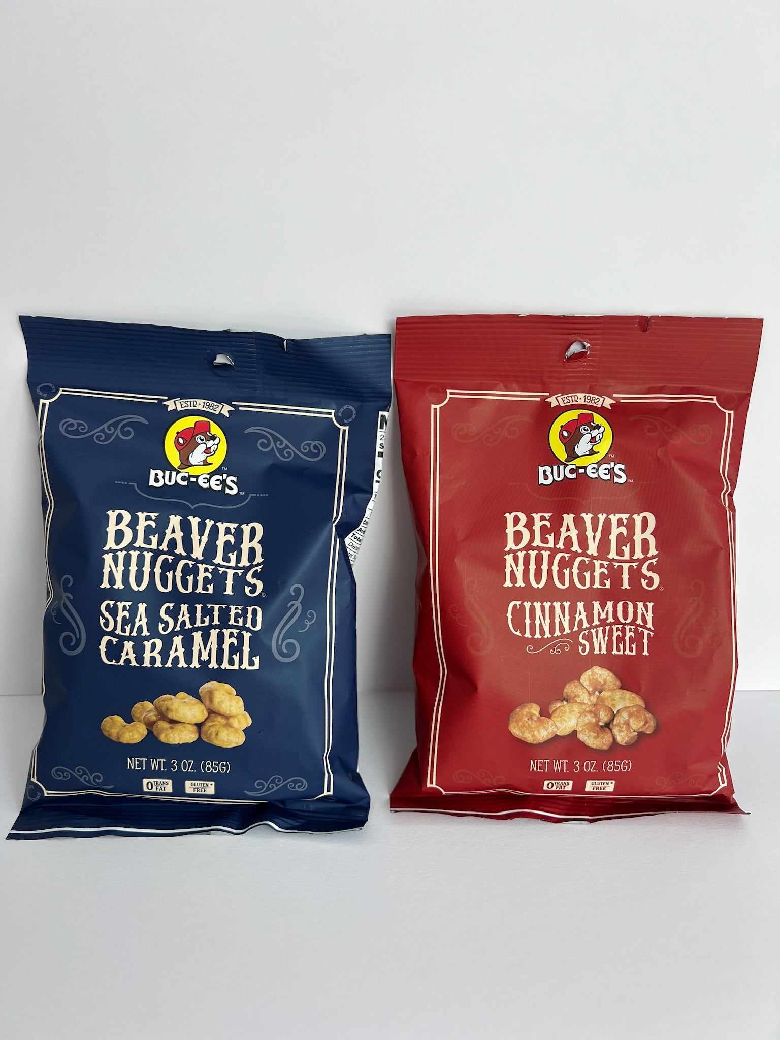 two 3 ounce bags of  buc-ee's beaver nuggets. one is maroon, cinnamon sweet flavor and the other is blue sea salted caramel flavor